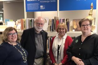 Australian Memory of the World Committee members and LibrariesACT staff stand in front of a collection of printed material 